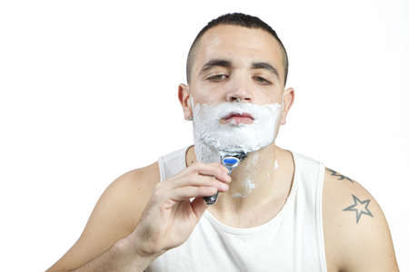 Young man shaving his beard with razor and foamの写真素材