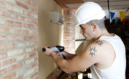 young worker making a hole in the wall with a drillのeditorial素材