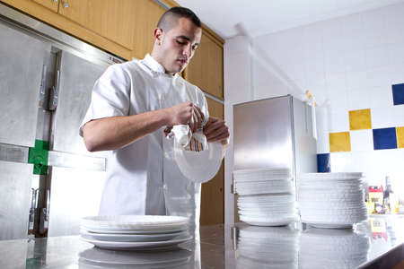 Young tired kitchen assistant dry dishesの写真素材