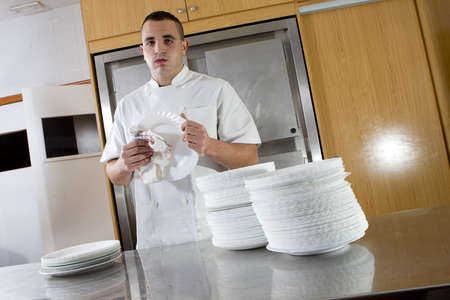 tired kitchen assistant drying dishesのeditorial素材
