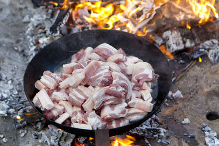 saucepan of bacon frying in fireの写真素材