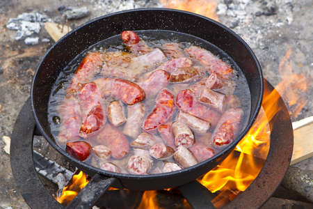 frying pan with garlic sausages on campfireの写真素材