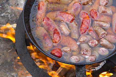 frying pan with garlic sausages on campfireの写真素材