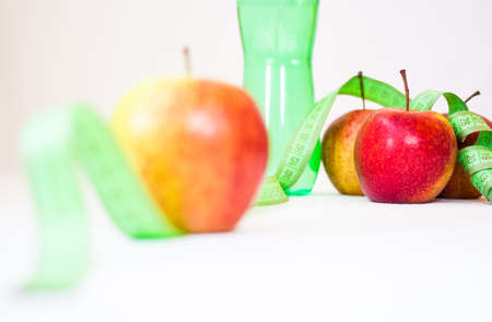bottle of water with measuring tape and a fresh appleの写真素材
