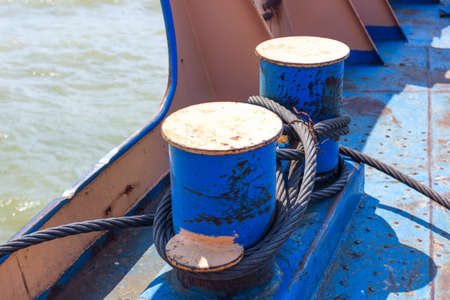metal cables coiled on blue anchor bollard, ship at seaの写真素材