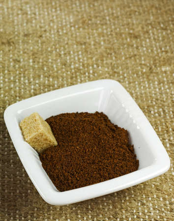 ceramic bowl with ground coffee and brown sugar cube on texture sack backgroundの写真素材
