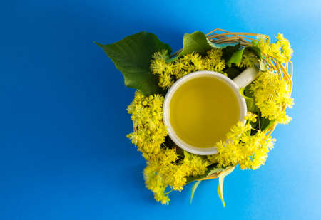 Cup of tea in braided wicker basket filled with lime blossomの写真素材