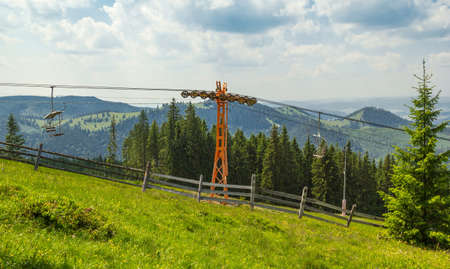 Empty chairlift in ski resort with green grass and blue skyの写真素材