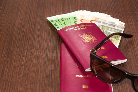Romanian passports with Euro banknote and sunglasses on wood tableの写真素材
