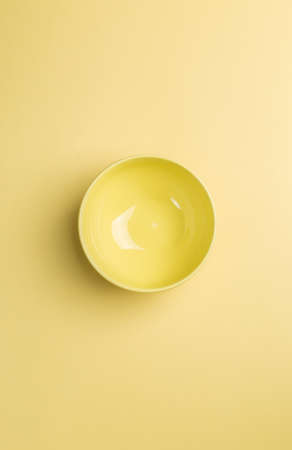 Yellow bowl on yellow background above view.Useful as a food backgroundの写真素材