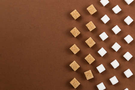 Brown and white sugar cubes on brown background. Useful for food presentation background.の写真素材
