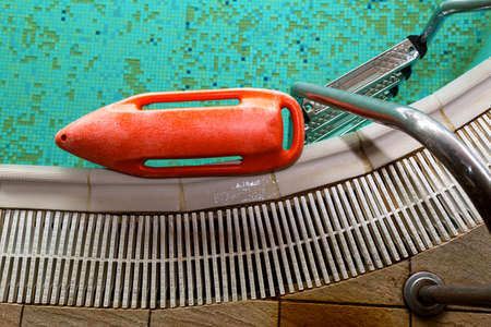 Red rescue buoy near the stairs in the swimming pool