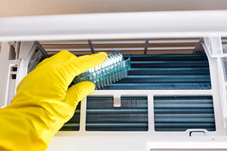 Person with gloves that clean the air conditione with brush