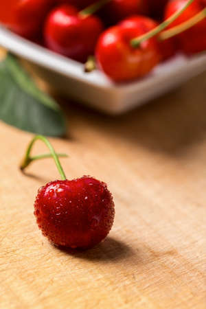 Cherry on wooden table with water drops. Macro shot of fresh cherry.の写真素材