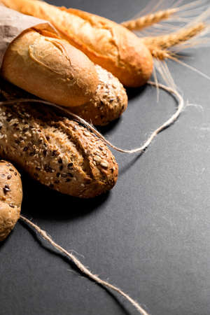 Different fresh bread with seeds, on black background table. Useful as bread presentation background.の写真素材