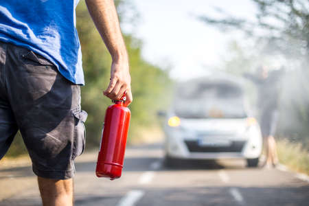 Man with a fire extinguisher helping a person with a car in the flame