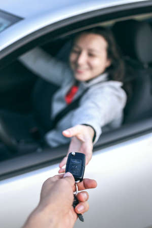 Happy young woman receiving the keys of her new car. Buy or rent a car concept.の写真素材