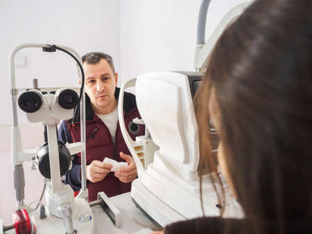 Man talks to the Ophthalmologist during an eyes exam with Slit Lamp. Eyes clinic examine procedure.