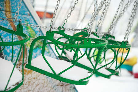Close-up of a swing chair in a carnival covered with snow. Swing chairs in the winter day.の写真素材