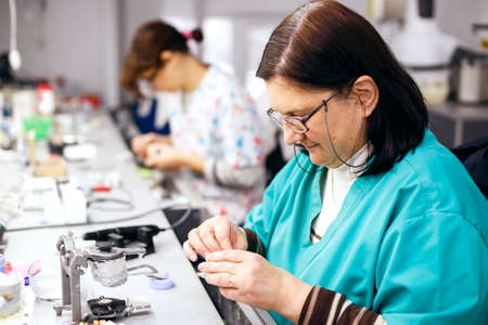 Female dental technician working on a dental prosthesis in the dental labの写真素材