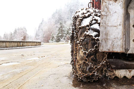 Closeup of snow chains mounted on a snowy car wheel.の写真素材