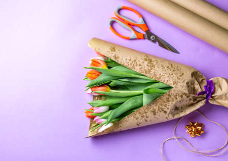 Bouquet of fresh colored tulips wrapped in brown paperの写真素材