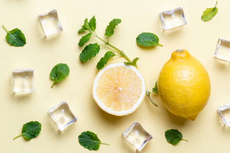 Above view of Fresh lemons with mint leaves over yellow backgroundの写真素材