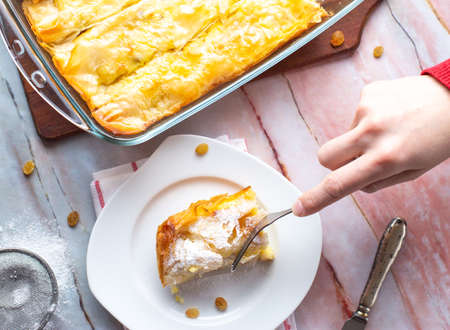 Person eating tasty pie cheese and raisins at the table, top view