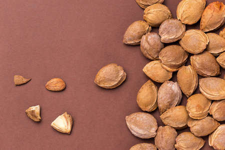 Top view of apricot kernels on brown background. Useful as food background