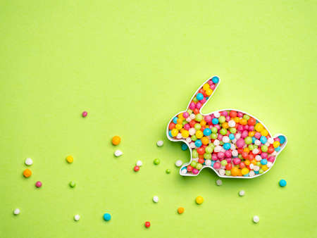 Creative layout of rabbit shape with colorful candies over green background and place for textの写真素材