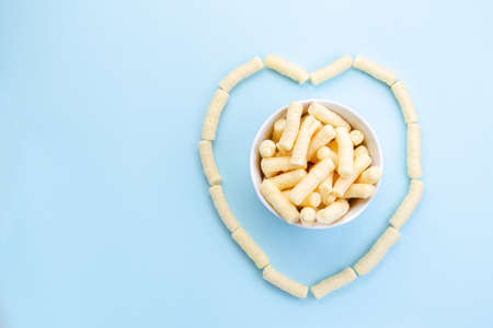 Heart made of Romanian pufuleti in white bowl over blue background. Love pufuletii conceptの写真素材