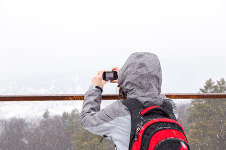 Woman taking pictures with the camera on a snowy day, Place for copy-space
