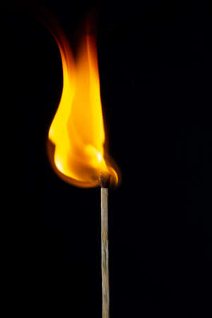Flame on the matchstick over dark backgroundの写真素材