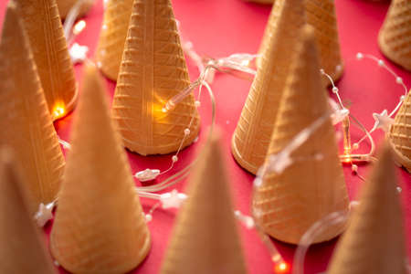 Many Ice cream cones with fir tree installation over red backgroundの写真素材
