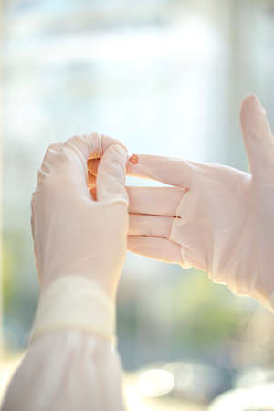 Hands with a broken medical glove.の写真素材