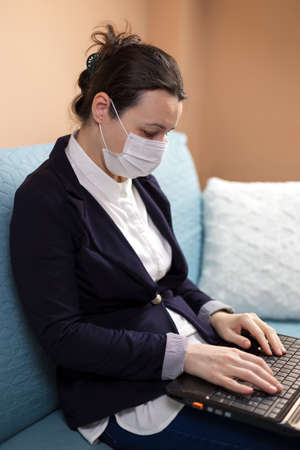 Woman with medical mask working from home, concept of home working during quarantineの写真素材