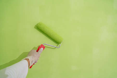 Painter with painting brush in hand painting a wall greenの写真素材