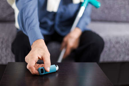 Person suffering asthma attack reaching inhaler. Senior person.の写真素材