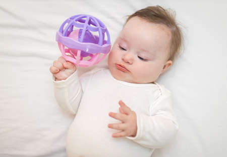 Cute Baby Girl Infant Stand on Back in Crib and Play With a Sensory Toyの写真素材