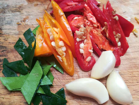 red chilli, yellow chilli, garlic and Kaffir Lime  leaf  on chopping wood boardの写真素材