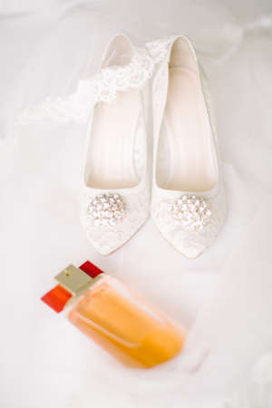 Bridal shoes on tulle. Gemstone and lace. Perfume bottle.の写真素材