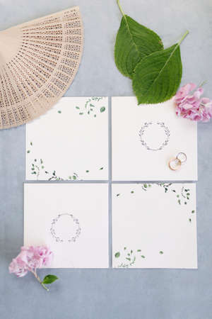 Wedding invitation. Empty white floor. Wedding rings. Fan and purple flowers. On the blue backdrop.の写真素材