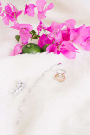 Wedding rings and jewelry. On a white background and pink bougainvillea leaves and lime.の写真素材