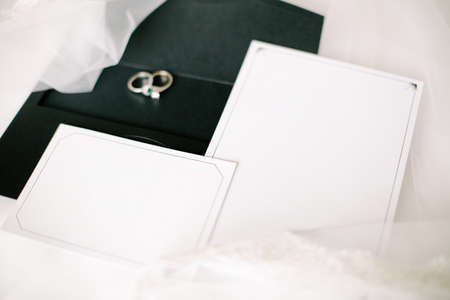Wedding or engagement invitation. Empty white writing area. Wedding rings. Tulle on a floor.の写真素材