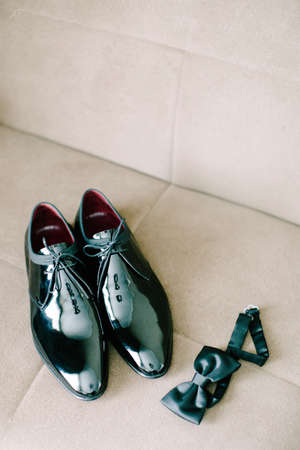 Black patent leather wedding shoes. Bow tie. Wedding reparations details. Indoor and close up.の写真素材