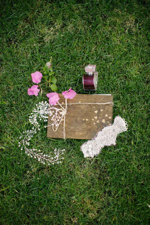 Wedding accessories. On the grass. Perfume, headband and notepad.の写真素材