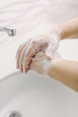 Woman washes her hands by surgical hand washing method. She washes his hands for at least 20...