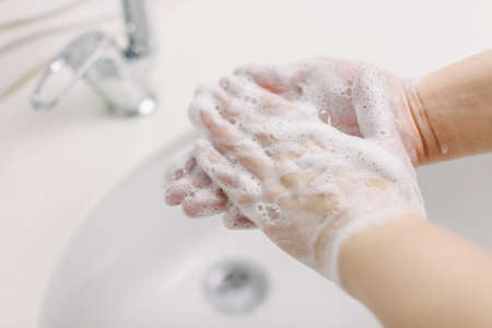 Woman washes her hands by surgical hand washing method. She washes his hands for at least 20...