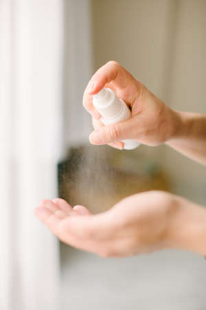 Hand spray. The woman is cleaning her hands with disinfectant spray. Methods of protection from...