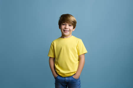 Fun young child enjoying rhythms in listening to music on headphones. Smiling blond boy in yellow t-shirtの写真素材